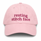 Pink cap with 'resting stitch face' text on a white background