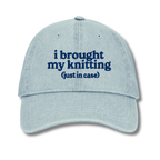 Light blue cap with text 'i brought my knitting (just in case)' on a white background