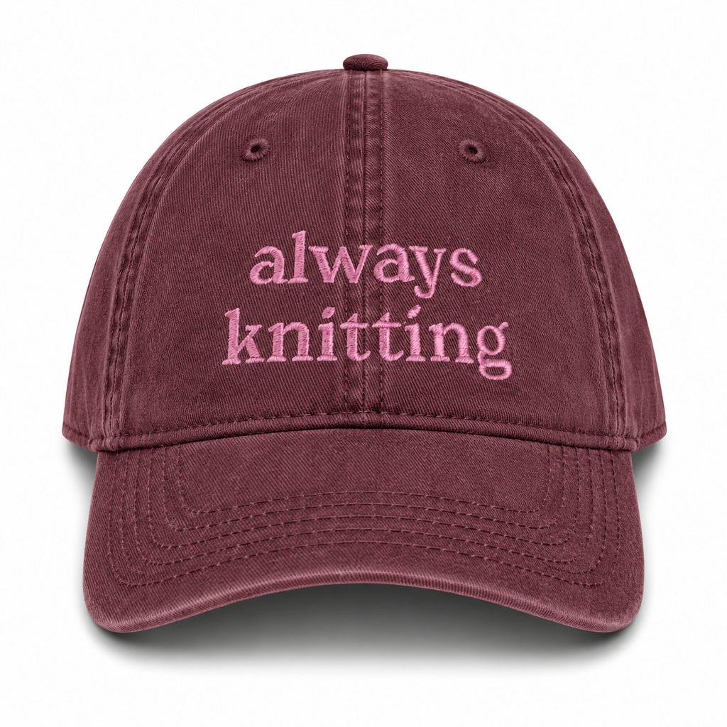 Maroon cap with 'always knitting' text on a white background