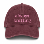 Maroon cap with 'always knitting' text on a white background