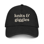 Black cap with 'knits & giggles' text on a white background