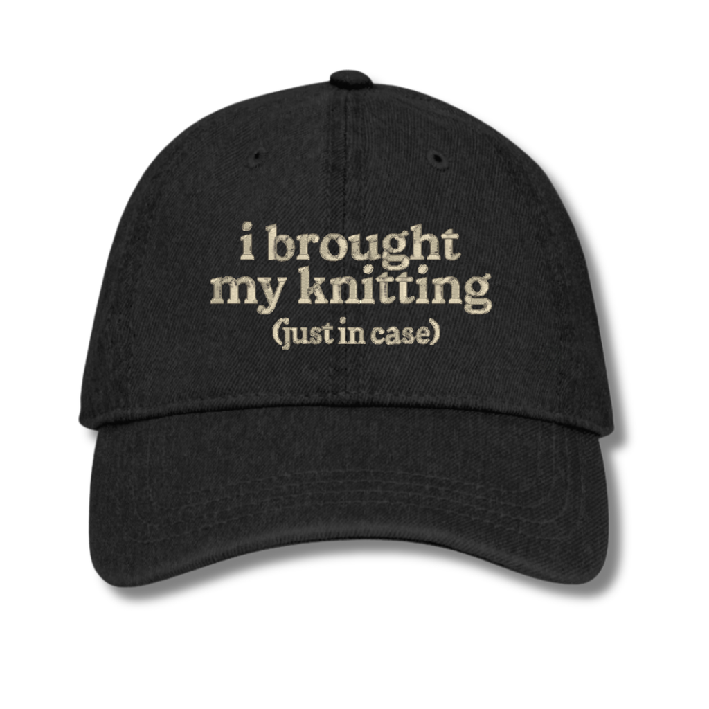 Black cap with text 'i brought my knitting (just in case)' on a white background