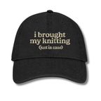 Black cap with text 'i brought my knitting (just in case)' on a white background