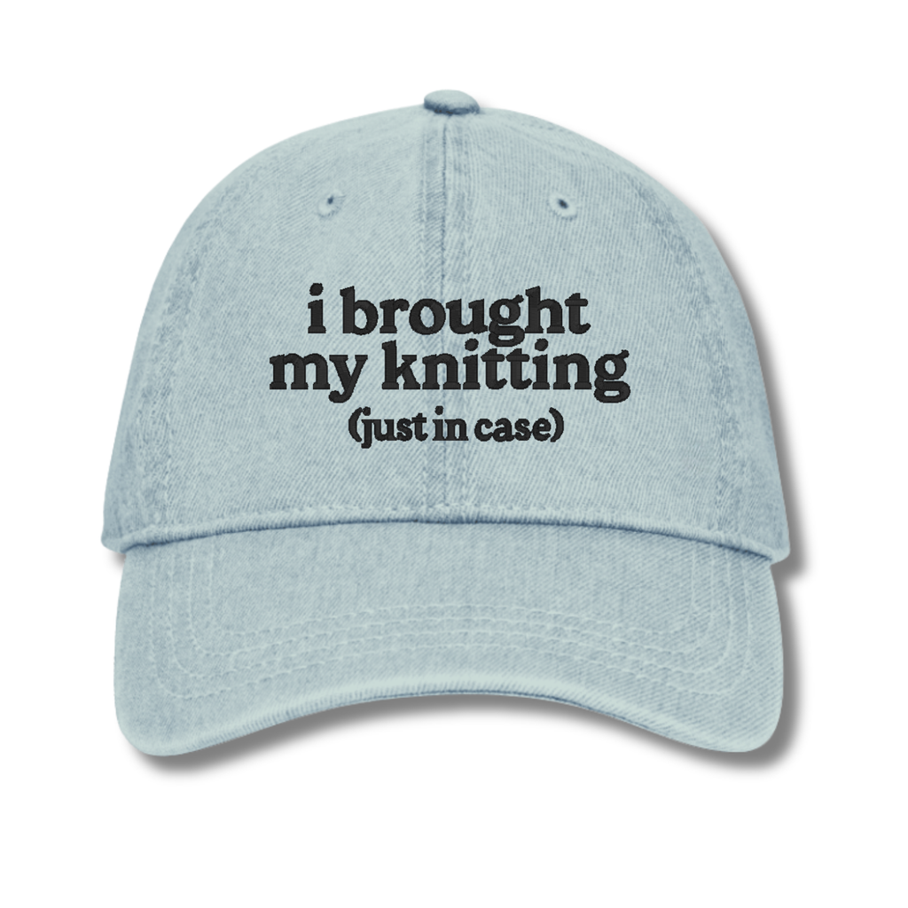 Light blue cap with text 'i brought my knitting (just in case)' on a white background