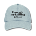 Light blue cap with text 'i brought my knitting (just in case)' on a white background