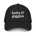 Black cap with 'knits & giggles' text on a white background