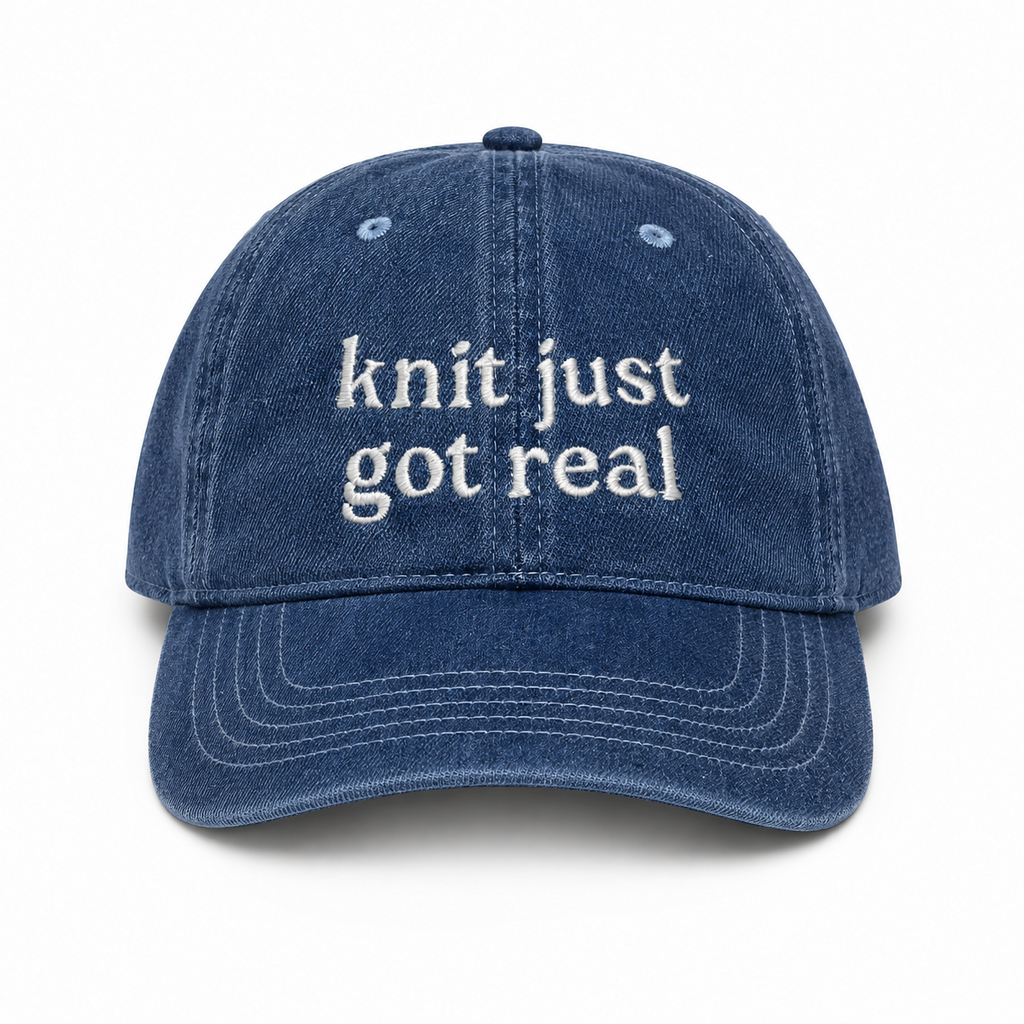 Blue denim cap with 'knit just got real' text on a white background