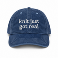 Blue denim cap with 'knit just got real' text on a white background