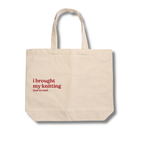 Beige tote bag with red text 'i brought my knitting (just in case)' on a white background