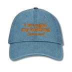 Blue cap with orange text 'i brought my knitting (just in case)' on a white background