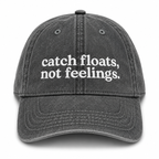 Black cap with 'catch floats, not feelings' text on a white background