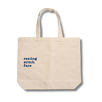 Beige tote bag with 'resting stitch face' text on a white background