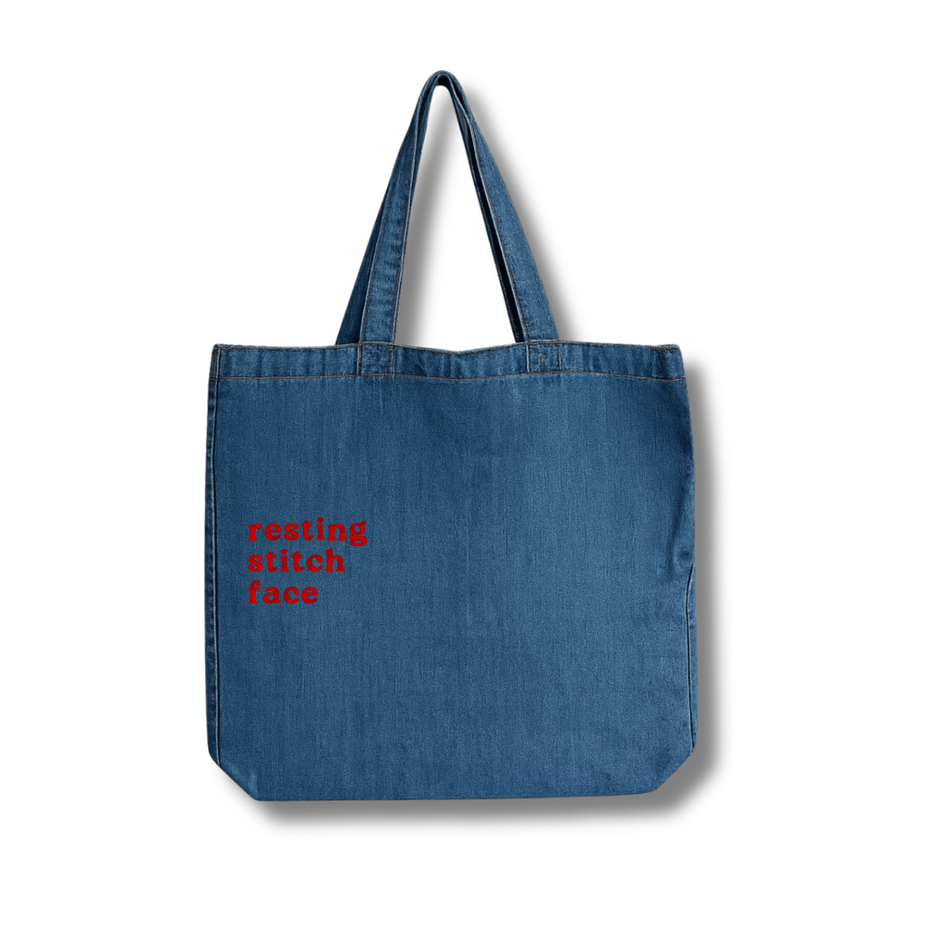 Blue denim tote bag with red text on a white background