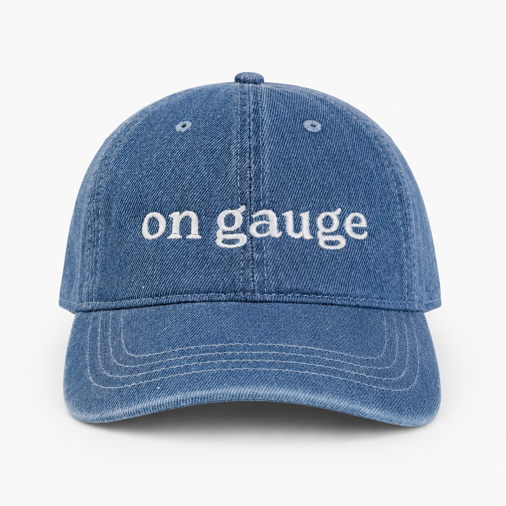Blue denim cap with 'on gauge' text on a white background