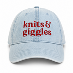 Light blue cap with 'knits & giggles' text in red on a white background