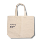 Beige tote bag with 'resting stitch face' text on a white background