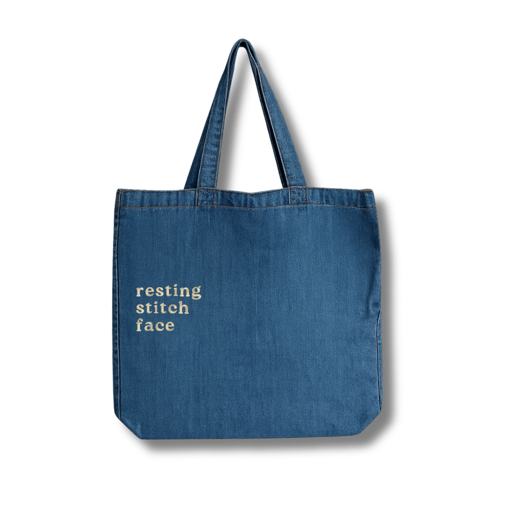 Blue tote bag with 'resting stitch face' text on a white background