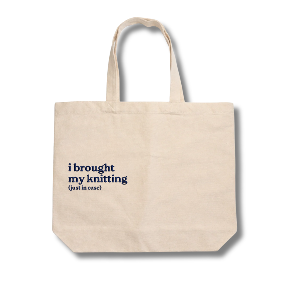 Beige tote bag with text 'i brought my knitting (just in case)' on a white background