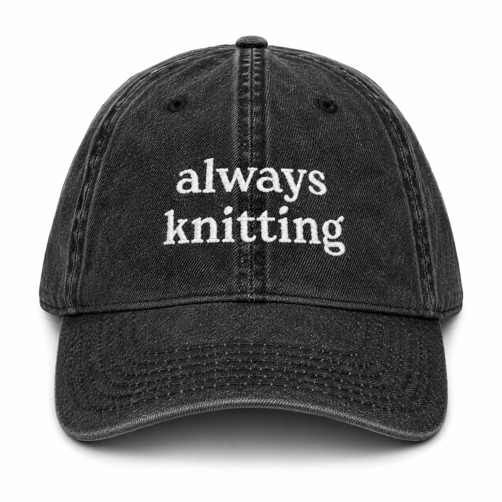 Black cap with 'always knitting' text on a white background
