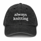 Black cap with 'always knitting' text on a white background