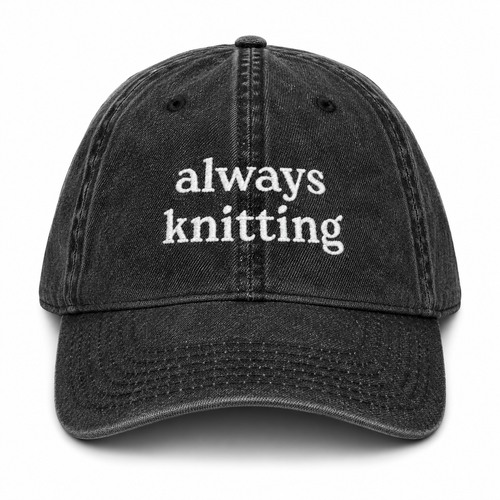 Black cap with 'always knitting' text on a white background