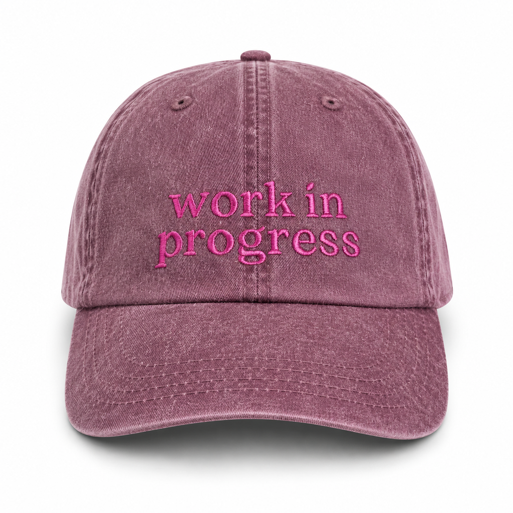 Pink cap with 'work in progress' text on a white background