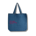 Blue denim tote bag with pink text on a white background