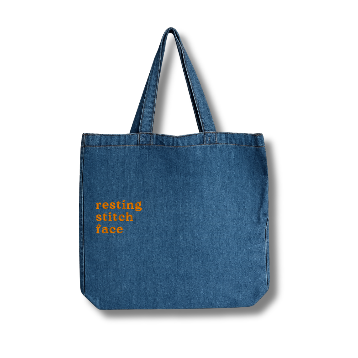 Blue denim tote bag with 'resting stitch face' text on a white background