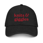Black cap with 'knits & giggles' text in red on a white background