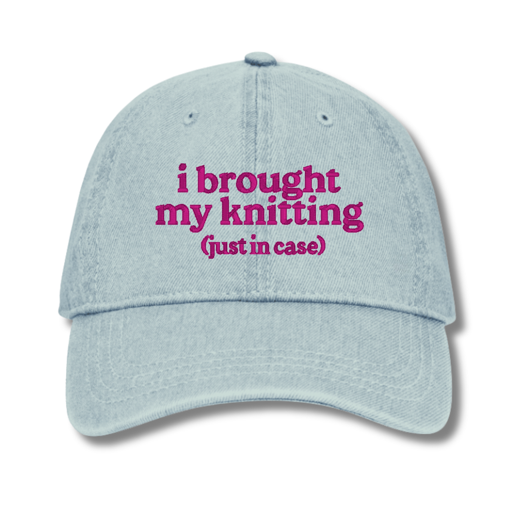 Light blue cap with pink text 'i brought my knitting (just in case)' on a white background