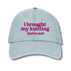 Light blue cap with pink text 'i brought my knitting (just in case)' on a white background