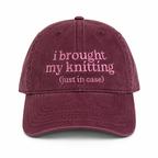 Maroon cap with pink text 'i brought my knitting (just in case)' on a white background