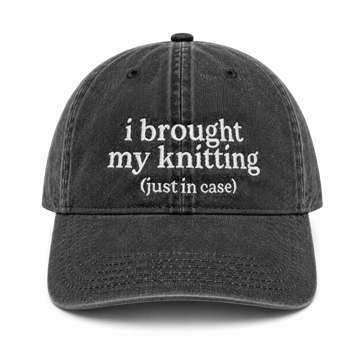 Black cap with white text 'i brought my knitting (just in case)' on a white background