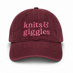 Maroon cap with 'knits & giggles' text in pink on a white background