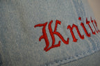 Light blue denim cap with red embroidered text on a blurred background