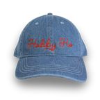 Blue denim cap with red embroidered text on a white background