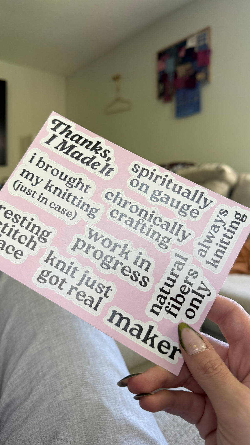 Hand holding a pink card with printed text in a casual indoor setting