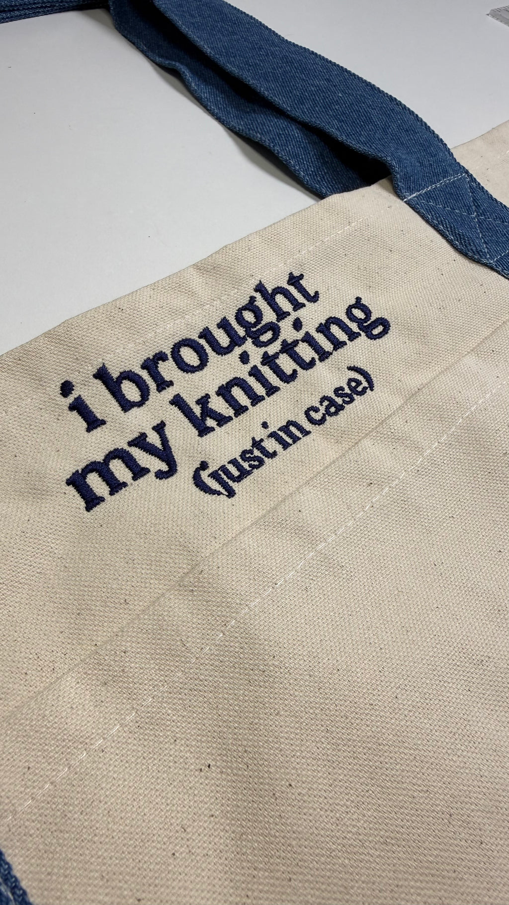 Textile product with 'i brought my knitting (just in case)' text on a blue and beige background