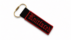 Black keychain with red text on a white background