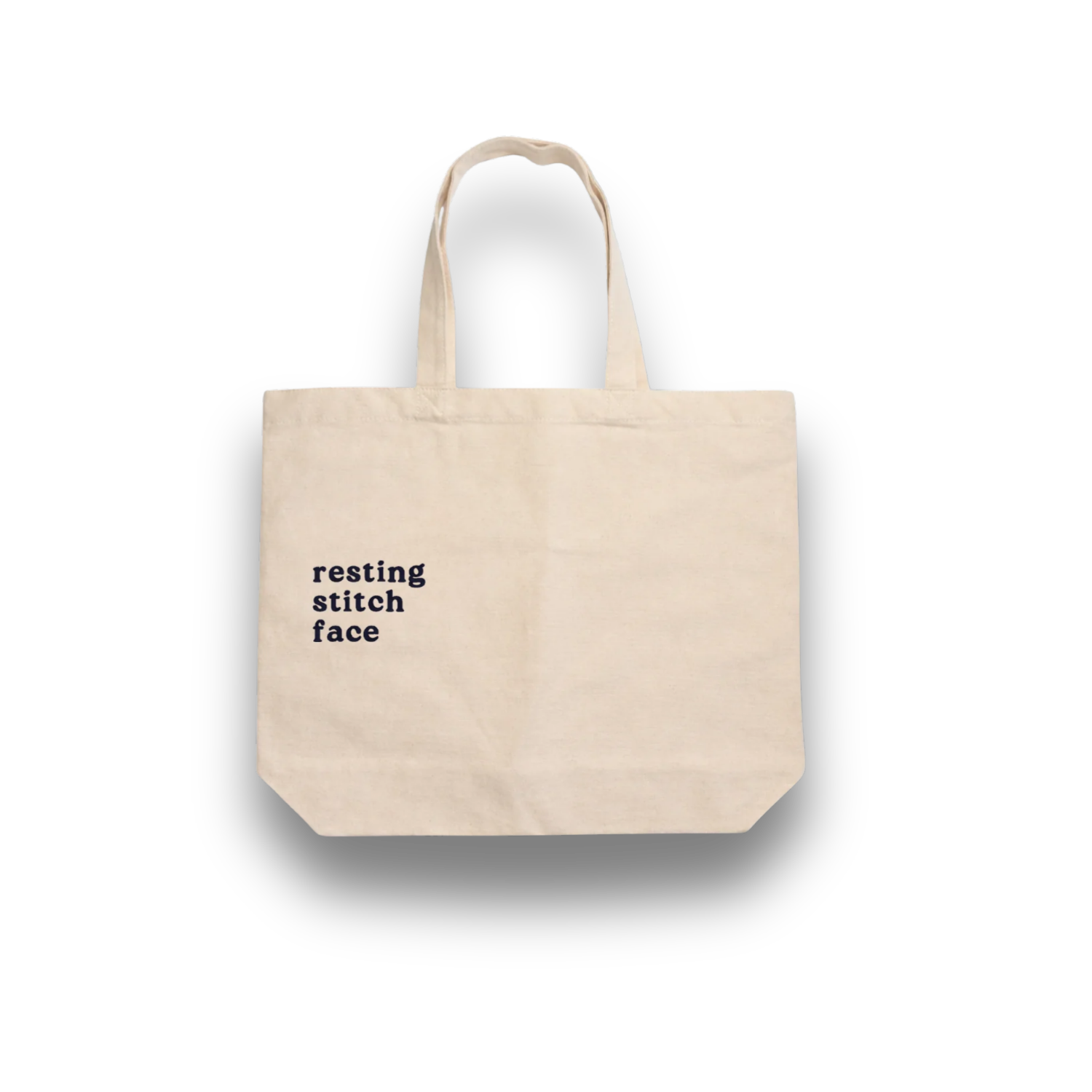 Beige tote bag with 'resting stitch face' text on a white background