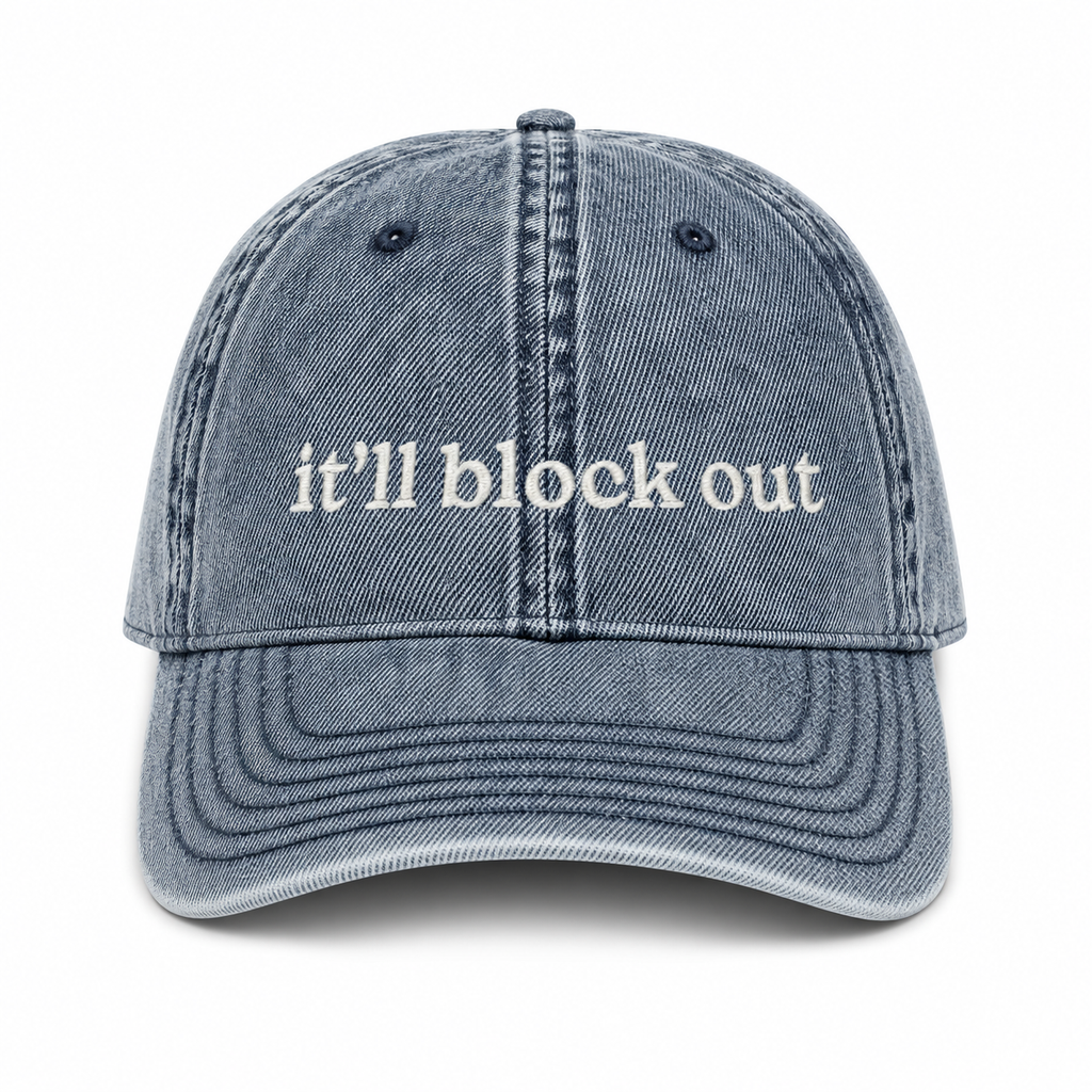 Blue denim cap with 'it'll block out' text on a white background