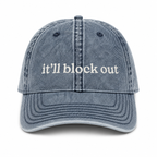 Blue denim cap with 'it'll block out' text on a white background
