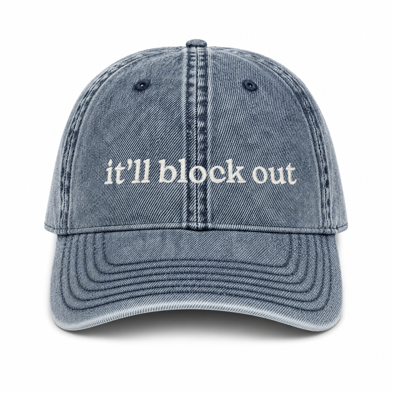 Blue denim cap with 'it'll block out' text on a white background