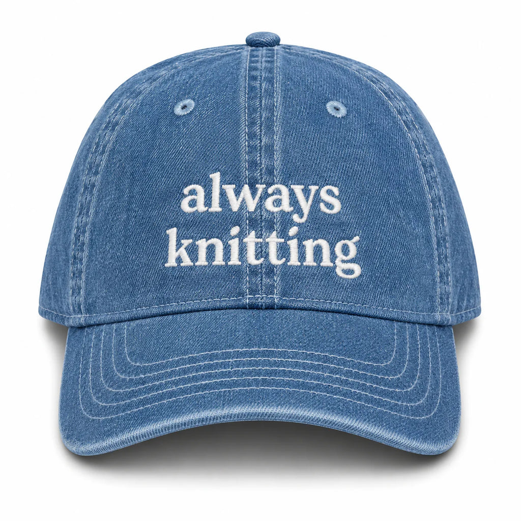 Blue denim cap with 'always knitting' text on a white background