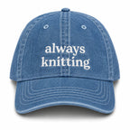 Blue denim cap with 'always knitting' text on a white background