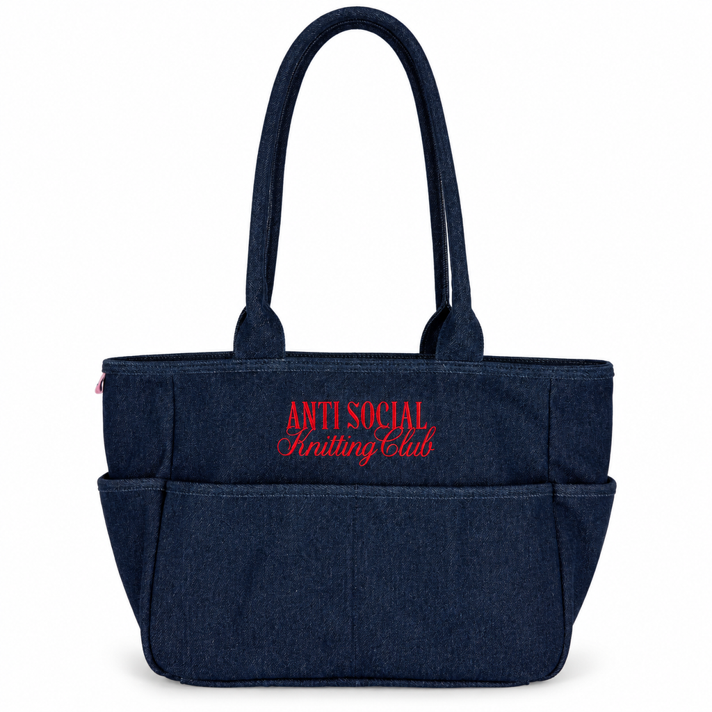 A dark navy blue denim tote bag with red embroidered text reading 'ANTI SOCIAL Knitting Club' on the front, set against a plain white background.