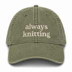 Green cap with 'always knitting' text on a white background
