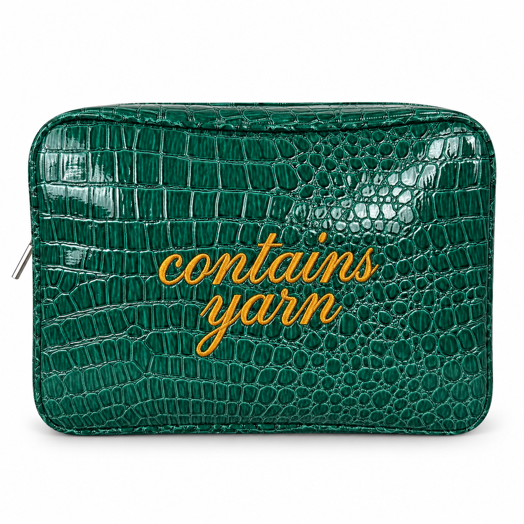 A green crocodile-embossed zippered pouch with the words 'contains yarn' written in gold cursive across the front, shown on a plain white background.
