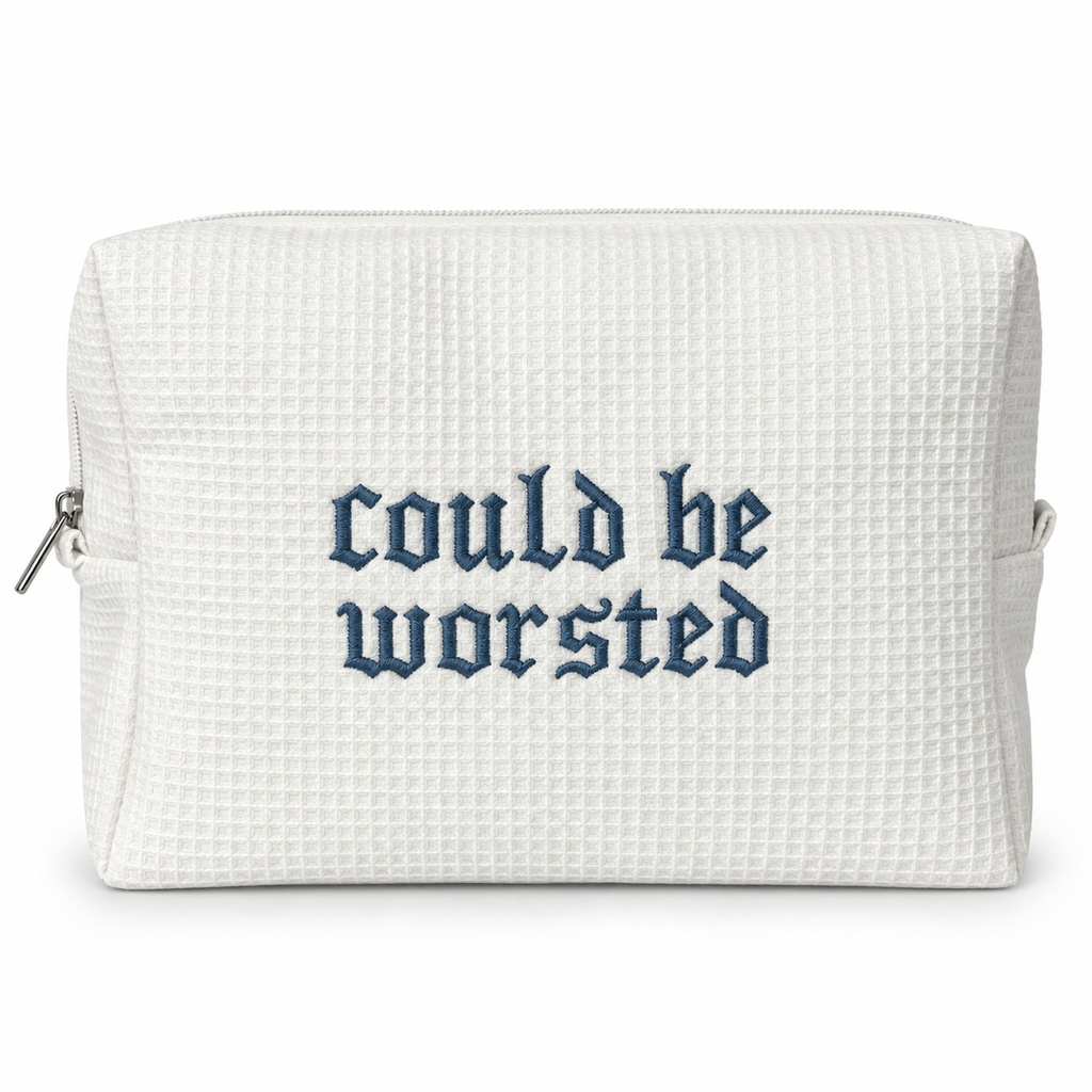 A white waffle-weave zippered pouch with the phrase 'could be worsted' embroidered in a dark blue Gothic font on the front, shown against a plain white background.