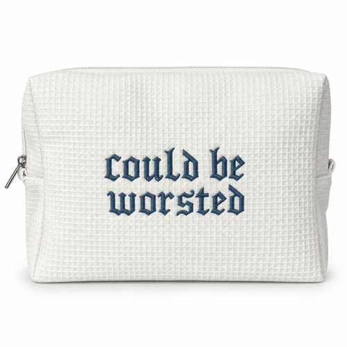 A white waffle-weave zippered pouch with the phrase 'could be worsted' embroidered in a dark blue Gothic font on the front, shown against a plain white background.